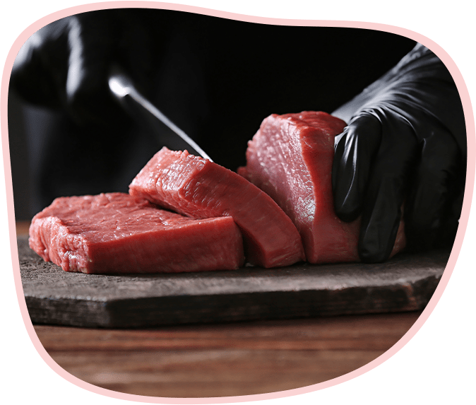 まな板の上で新鮮な赤身肉をナイフでカットしている様子